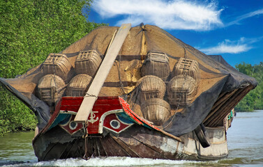 Heavy loaded rice cargo traditional vietnamese sampan style boat with typical painted stylized bow...