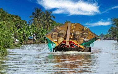 Beautiful Mekong Delta landscape, one traditional typical vietnamese sampan rice cargo boat, green palm trees - Mekong Delta, Vietnam