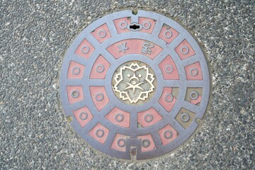 Closeup of a Japanese manhole cover, featuring a unique design with a circular design