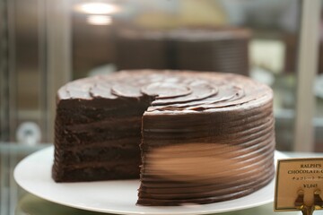 Closeup of a layered chocolate cake in a glass display case