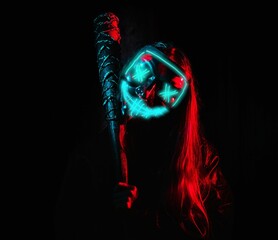 A crazy girl in an ominous neon mask holding a wired baseball bat on her shoulder, in a dark room