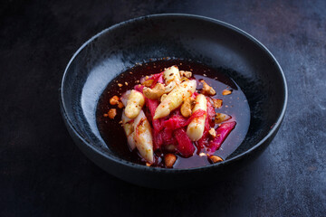 Deutscher Rhabarber Spargel Salat mit Cashew Nüssen in Himbeersauce serviert als Nahaufnahme in einer Nordic Design Schale mit Textfreiraum