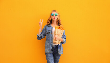 Portrait of stylish happy young woman posing with grocery shopping paper bag with long white bread...