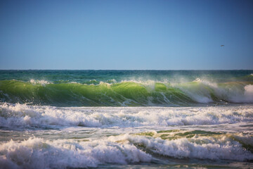 Fototapeta na wymiar Big ocean waves, green sunrise wave and cloudscape over the sea water