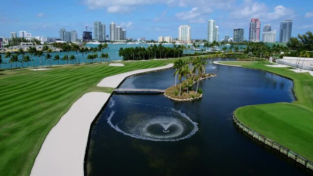 Drone view of artificial reservoir and small island with palms inside in middle of golf course in Fisher Island. Spectacular scenery on Miami Beach with yachts and skyscrapers