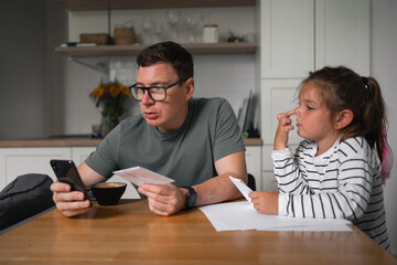 Father and child girl doing origami crafts together. Modern parenthood, weekend education...