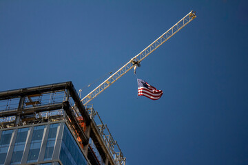Tower Crane with an American flag near a modern office building under construction