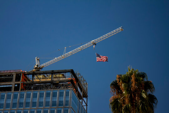 Tower Crane with an American flag near a modern office building under construction
