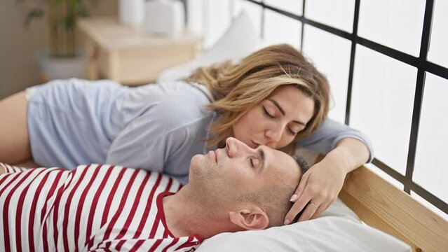 Man and woman couple lying on bed kissing while sleep at bedroom