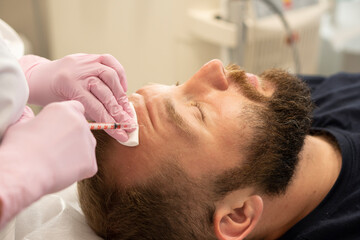 Men's cosmetology. Cosmetologist makes botulinum toxin beauty injection procedure in forehead...