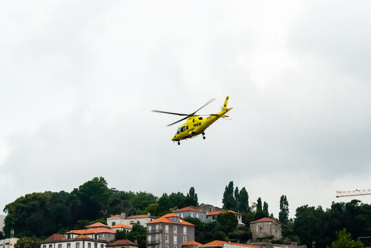 PORTO, PORTUGAL - JUNE 18, 2014: An INEM air ambulance helicopter takes off above the Douro river in overcast conditions. INEM is Portugal's national medical emergency institute.
