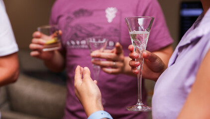 Hands grasp glasses, a toast to celebration, connection, and indulgence; alcohol and champagne represent joy, social bonding, and festivity