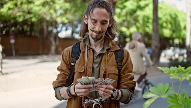 Young hispanic man tourist wearing backpack counting dollars at park