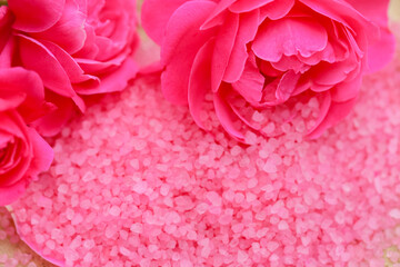 Aromatic salt with rose extract and pink rose flowers close-up. Rose salt with rose extract and fragrance. Aromatherapy and cosmetics.