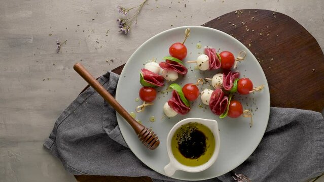 Italian style appetizer, antipasto skewer or caprese on a stick with basil, salami, mozarella and tomatoes.