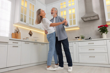 Happy affectionate senior couple dancing in kitchen, low angle view