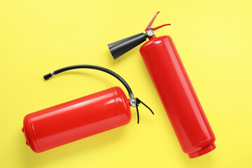 Two fire extinguishers on yellow background, flat lay