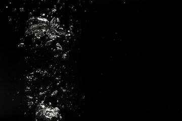 Air bubbles in water on black background, space for text
