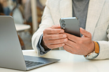 Man using smartphone at table in outdoor cafe, closeup