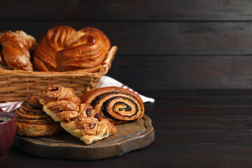 Different tasty freshly baked pastries on wooden table, space for text