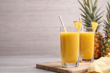 Tasty pineapple smoothie on wooden table, space for text