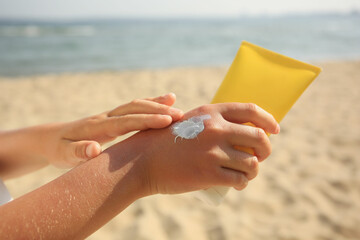 Child applying sunscreen near sea, closeup. Sun protection care