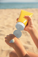 Child applying sunscreen near sea, closeup. Sun protection care