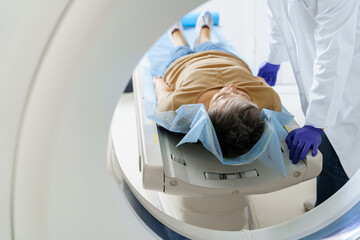 Radiologist controls MRI or CT Scan with patient undergoing procedure. High Tech medical equipment