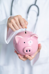 Doctor holding piggy bank and putting coin. and Healthcare cost, Money Saving, Health Insurance,...