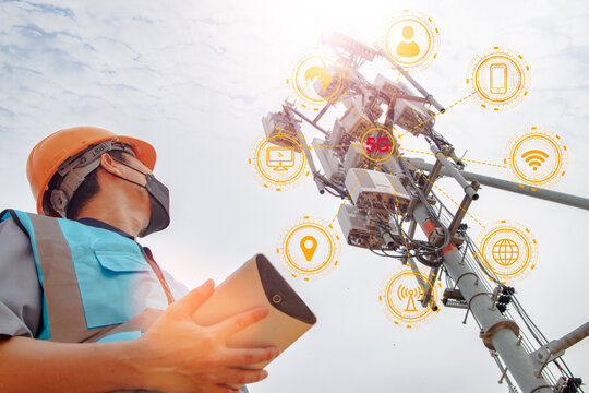 Asian male engineer helmet working field check in using tablet in tall building to check telecommunication signal tower, 5G technology network, telecommunication tower, internet network information.