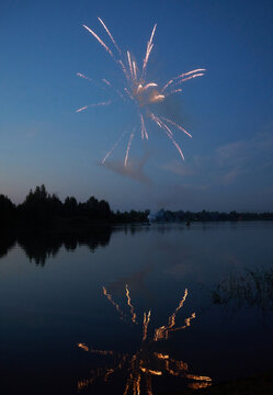 Holiday fireworks at sunset over a picturesque lake. Fourth of July.
