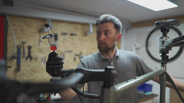 Bicycle mechanic holding syringe with brake fluid during brake bleeding process. Cycle repairman injects brake fluid into hydraulic brakes on bike in workshop. Maintenance cycle brake disc system. 