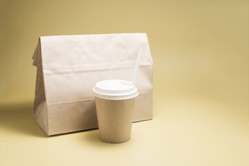 The concept of food delivery. A paper bag with food and a paper cup on a light background.