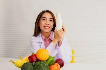 Obraz premium Portrait asian professional dietician coat happily on table with fruits and vegetables to spread online media presentation recommending drink milk vegetables fruits with nutritional value health care.