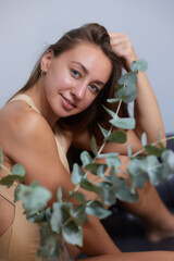 Alluring in good shape bewitching female model over 20s in sandy clothes cuddling the fern leave...
