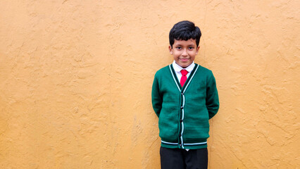 Dark-haired 9-year-old Latino boy in a public school uniform is excited and happy about the return...