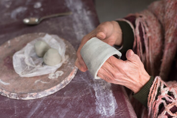 detail of the hands of a 70-year-old woman working with her fingers on a piece of clay pottery, selective focus on the hands