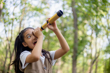 Happy Little Asian girls looking ahead and smiling child with the binoculars in the park. Travel...