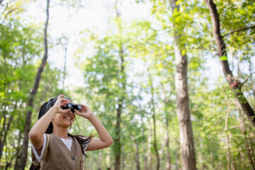 Happy Little Asian girls looking ahead and smiling child with the binoculars in the park. Travel...