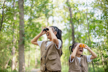 Happy Little Asian girls looking ahead and smiling child with the binoculars in the park. Travel...