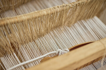 Vintage color thread behind a manual wood loom, old weaving loom.