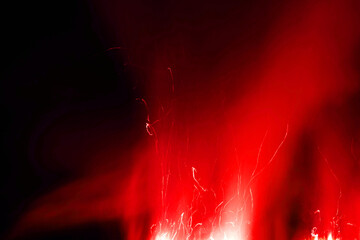 Dark black background with red sparks, charcoal, embers and smoke. Overlay effect of burning coals, grill, hell or bonfire with glow, red sparks and fog on black background.