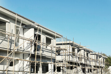 Housing real estate business presentation background with perspective row of housing project under construction on site and scaffolding on beautiful clear blue sky. - 637187405