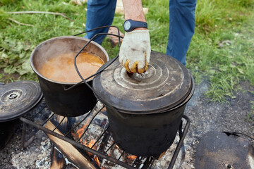 Hiking pot, Bowler in the bonfire. in cauldron at the stake. Traveling, tourism, picnic cooking,...