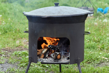 Hiking pot, Bowler in the bonfire. in cauldron at the stake. Traveling, tourism, picnic cooking,...