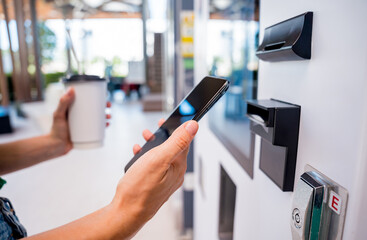 Young woman paying for coffee at vending machine using contactless method of payment 