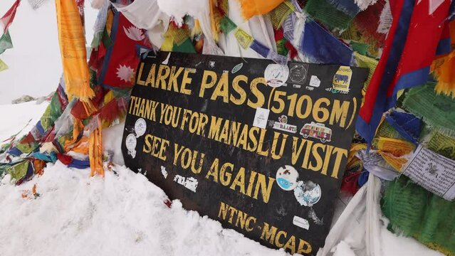 Sign and flags at the Larke Pass on the Manaslu Circuit Trek, Nepal.