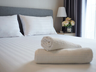White soft pillows on the neatly clean bed with blurred foreground of baht towels - home , coziness and clean concept 