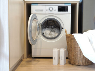 Washing machine with cloth loaded , laundry detergent and softener bottles lay on the front - household work concept