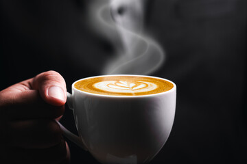 Businessman manager holding hot latte coffee cup relaxation in the morning. Coffee break mug in dark black background with copy space for text.